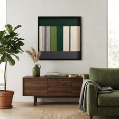 Textured wool wall hanging in a black frame styled next to a moss green sofa and a large indoor fiddle leaf fig.