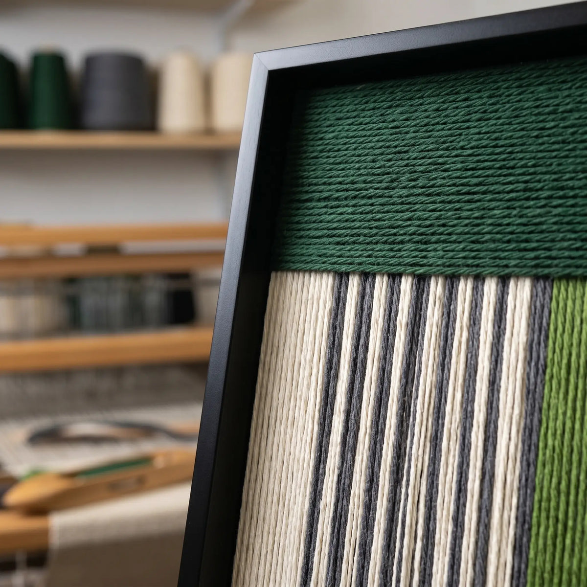 Close-up shot of the top corner of the framed fiber art showing the horizontal and vertical soft cotton cord textile patterns.