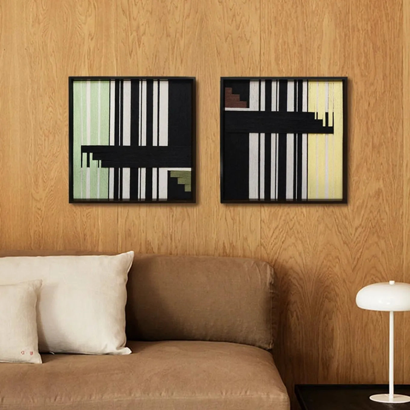 Timeless Moments hand-woven yarn wall art diptych with alternating emerald and ivory stripe panels and contrasting black bands in natural wood frames, displayed above a sofa on a wood-paneled wall.