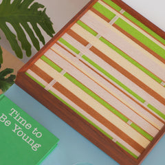 Tree Ah Tree yarn woven wall art styled on a blue desk next to a plant and stationery