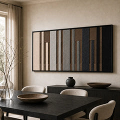The Umber Columns geometric hand-woven wool tapestry provides a striking focal point over a dark wooden dining table in a contemporary dining room.