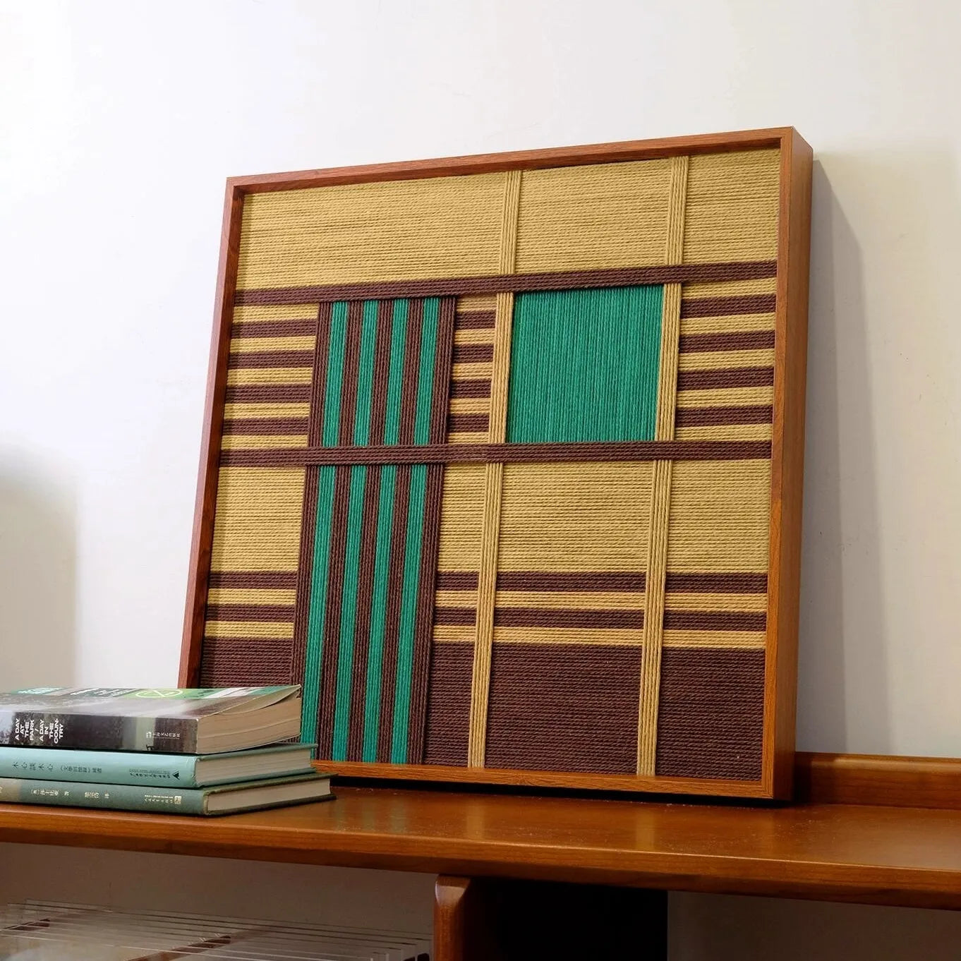 Vast Horizon hand-woven yarn wall art featuring alternating mint green, oak wood, and chocolate brown vertical stripes above an ocean-blue lower panel in a natural wood frame