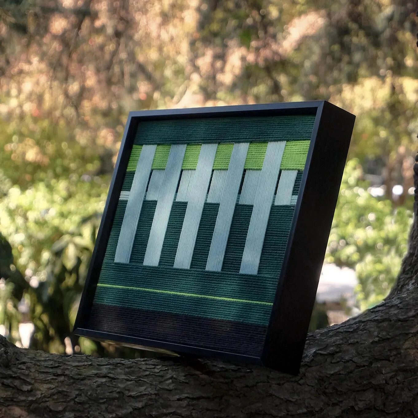 Angled view of Velvet Vine yarn wall art highlighting dense stitch work of premium wool and crisp transitions between green and white stripes
