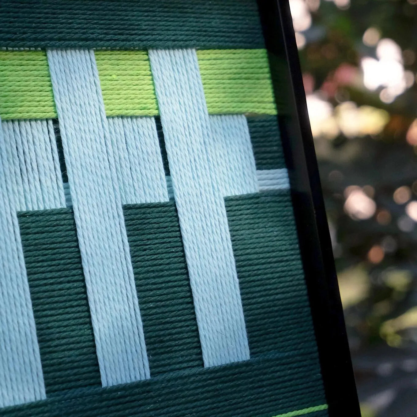 Velvet Vine wall art on tree stump, featuring uniform lime green and white stripe blocks woven from premium wool