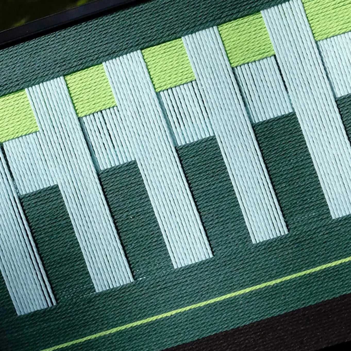 Macro shot of Velvet Vine yarn wall art emphasizing tight stitching and color depth of green and white yarns