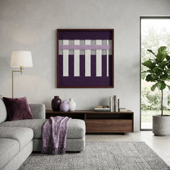 Textured wool wall decor in a dark frame placed above a wooden credenza in a bright, contemporary lounge with a grey sectional.