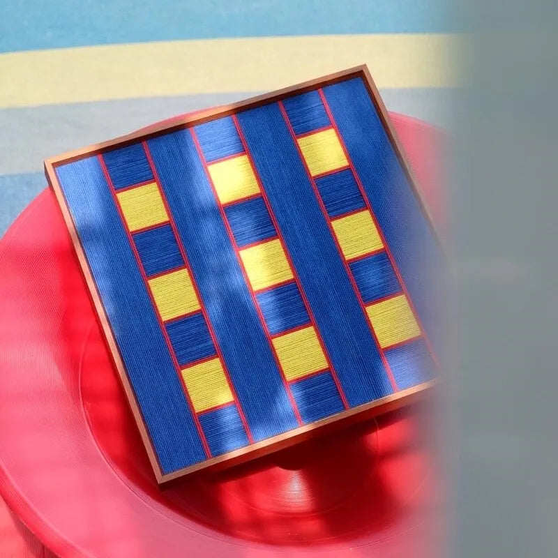 Window Peek at Moon wall art styled against a red surface to emphasize its alternating blue stripe pattern and bold color contrast