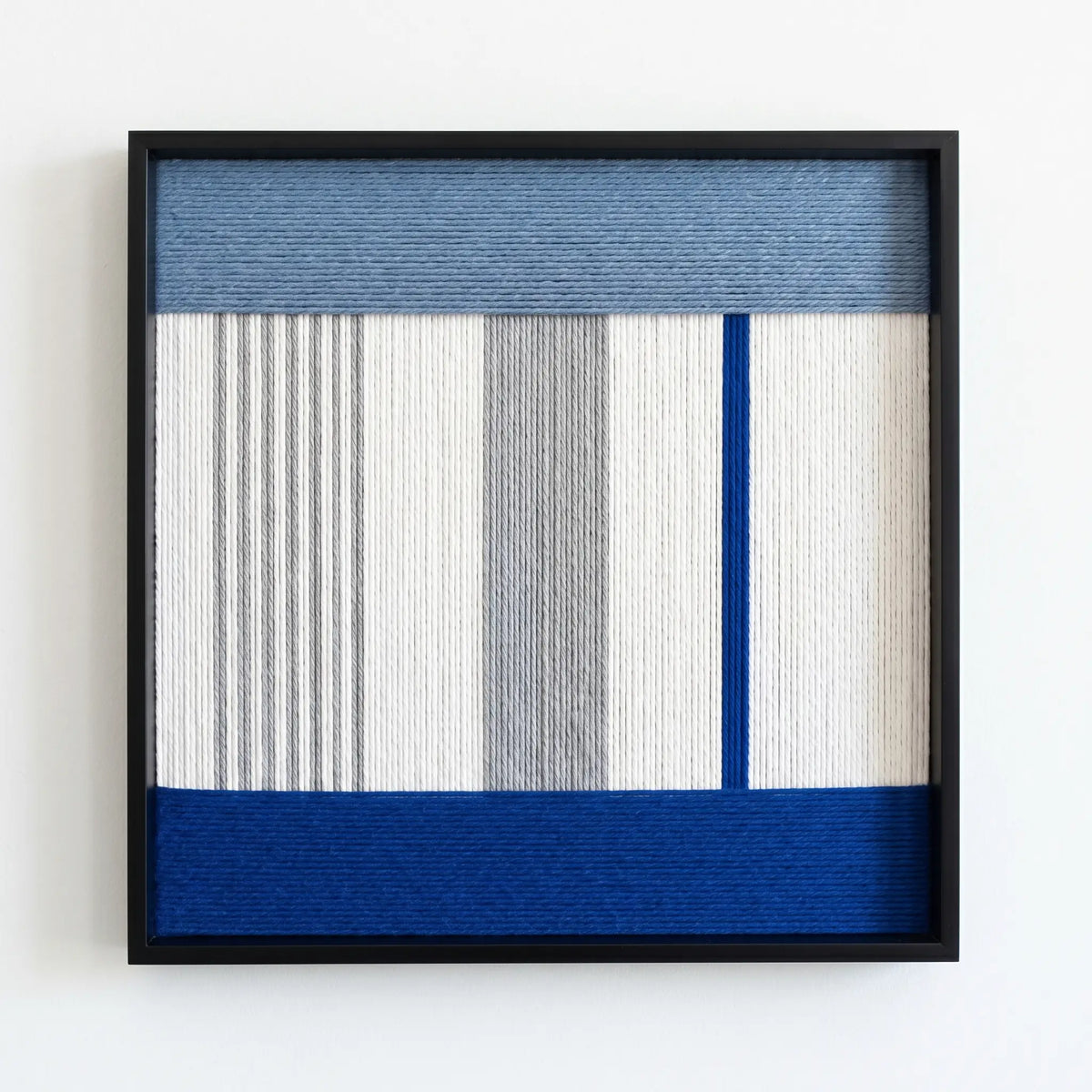 Professional studio shot of the Absolute Zero soft cotton cord wall art featuring blue and grey geometric patterns in a black frame.