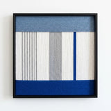 Professional studio shot of the Absolute Zero soft cotton cord wall art featuring blue and grey geometric patterns in a black frame.