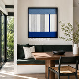 Absolute Zero hazy blue white gray and cobalt textile wall art featured above a dark green banquette in a sunlit modern dining nook.
