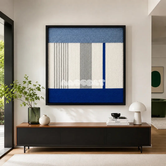 Absolute Zero hazy blue white gray and cobalt textile wall art displayed above a dark cabinet in a bright modern entryway.