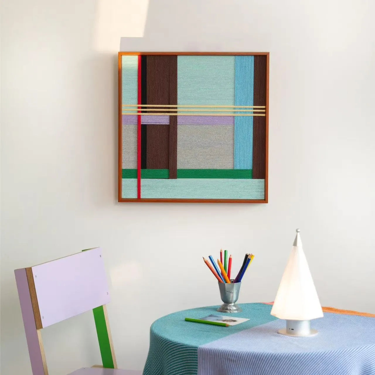 Side angle view of the framed fiber art on a white wall, emphasizing the depth of the wooden frame and the tactile texture of the wool.