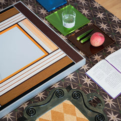 Angled close-up of the fiber art mirror frame resting on a surface, highlighting the depth of the wood and the intricate brown and beige wool weaving.