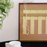 Hand-held view of Autumn Mountain fiber wall art showing its square proportions and precise stripe alignment.