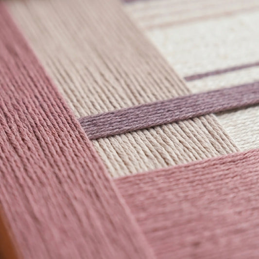 Extreme angled macro close-up of the Ballet Whispers hand-woven textile art, highlighting the dimensional dusty rose, plum, and cream textured yarn.