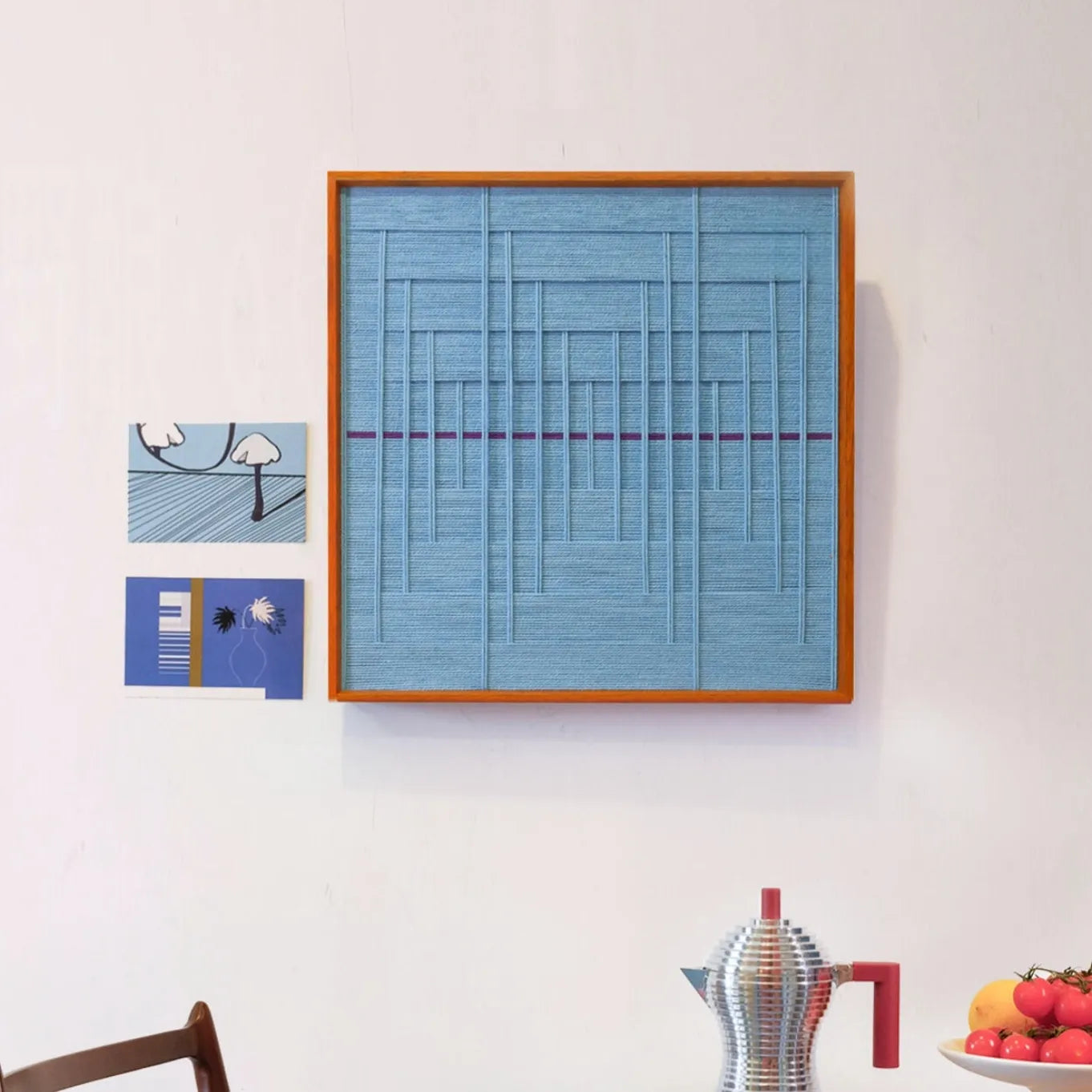 Blue Bridge Over the Pond hand-woven wool yarn wall art with top grid of vertical and horizontal lines and a solid blue lower panel, framed in natural wood

