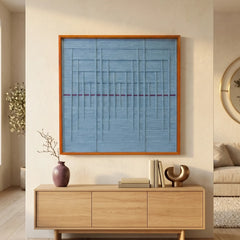 Large square Blue Bridge Over the Pond textile wall art featuring a light blue woven background with a red horizontal stripe, hanging above a light oak sideboard in a sunlit living room.