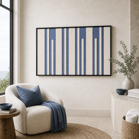 Framed Blue Cadence hand-woven wall art displayed above a cozy armchair with a blue throw in a bright living room.