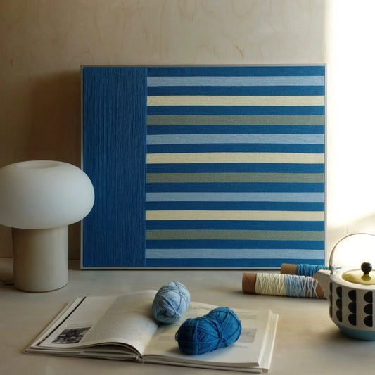 Blue Night hand-woven yarn wall art featuring bold blue stripe pattern, styled alongside matching yarn balls to highlight texture and color coordination
