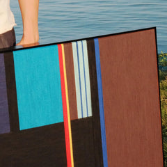 Angled view of Blue Tide Night Run yarn wall art showcasing the tactile looped wool texture and crisp transitions between blue and black stripe panels.
