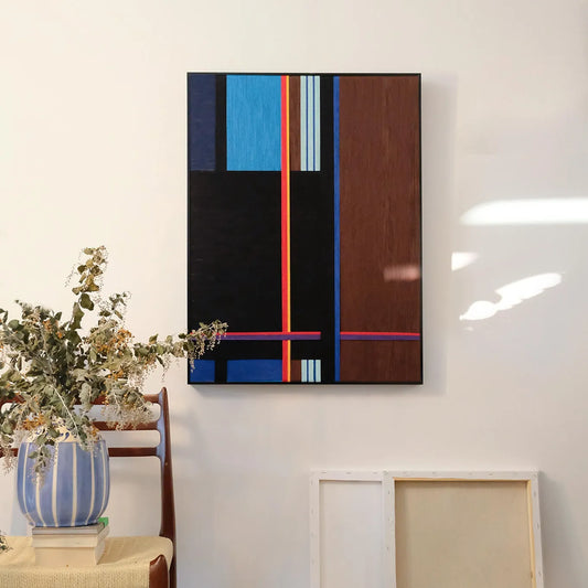Blue Tide Night Run hand-woven wool yarn wall art featuring bold vertical stripes in ultramarine and sky blue, contrasted by black and dark walnut panels, accented with a slender red stripe, all set in a natural wood frame and displayed above a console table.
