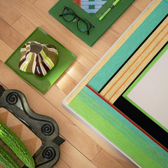 Flat‑lay view of Breathing Like Fresh Grass yarn art on a tabletop with weaving tools and greenery, highlighting the tactile looped wool texture.

