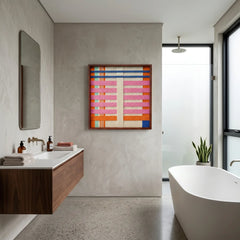 Vibrant framed hand-woven wool tapestry displayed in a modern luxury bathroom with a floating wooden vanity and a freestanding white bathtub.