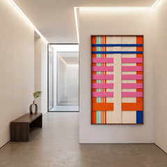 A large California Rhythm hand-woven wool tapestry displayed in a bright modern hallway above a wooden bench.
