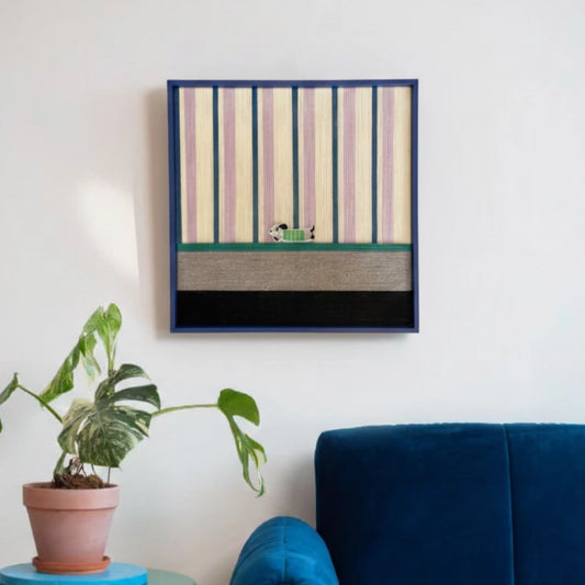Framed textured fiber wall art styled in a bright living space above a deep blue velvet sofa with a potted plant.