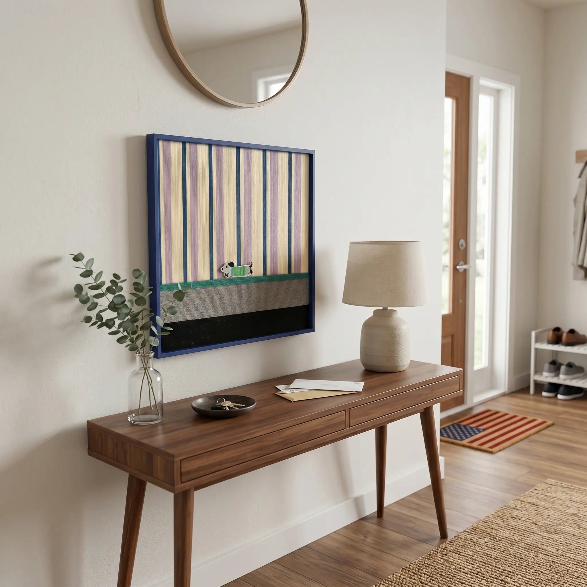 Framed striped and color-blocked textile art displayed above a dark wood console table in a minimalist entryway foyer.