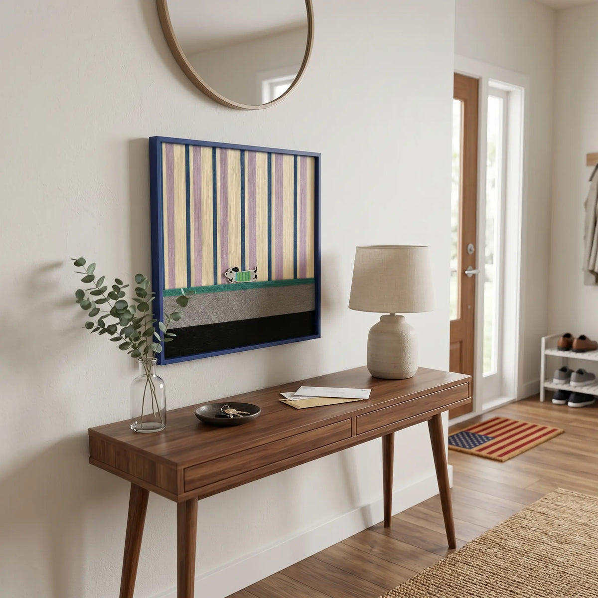 Framed striped and color-blocked textile art displayed above a dark wood console table in a minimalist entryway foyer.