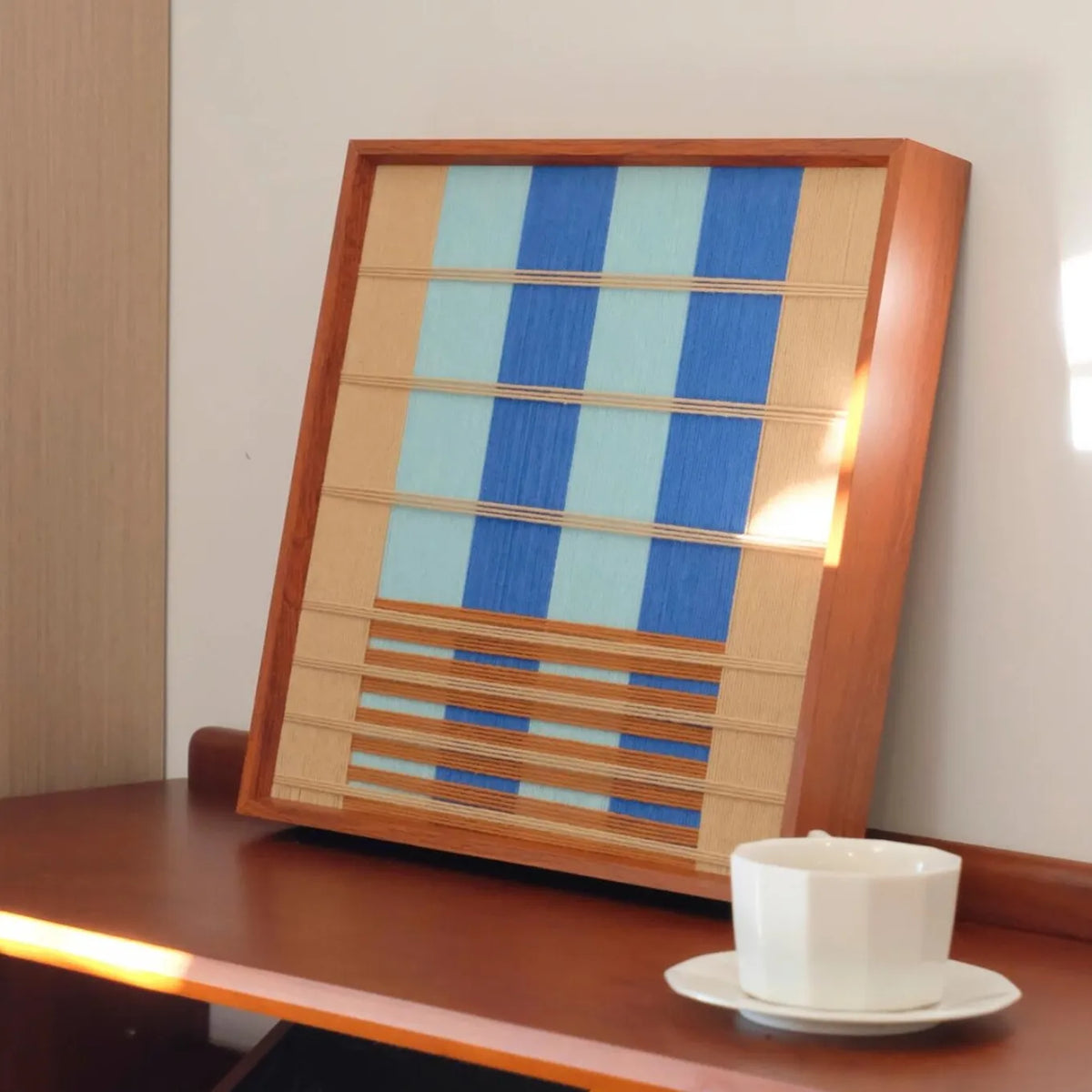 Mountain & River yarn wall art displayed on a table next to a cup, showcasing precise stripe alignment and smooth soft cotton cord texture