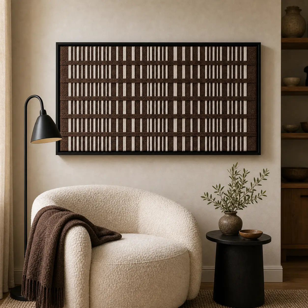 Earth-toned Cocoa Cadence framed wall art styled in a cozy lounge reading nook positioned next to a white curved armchair and black side table.