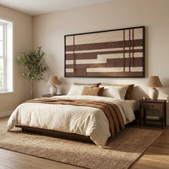 A beautiful framed hand-woven wool tapestry displayed gracefully above a styled bed with matching brown and cream accents in a cozy bedroom.