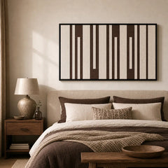 Large framed Cocoa Pillars wool tapestry hanging elegantly above a neatly styled bed with matching brown bedding.