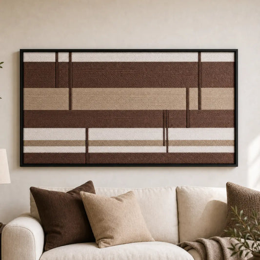 Large framed Cocoa Strata hand-woven wall art hanging elegantly above a cozy beige sofa in a neutral living room.