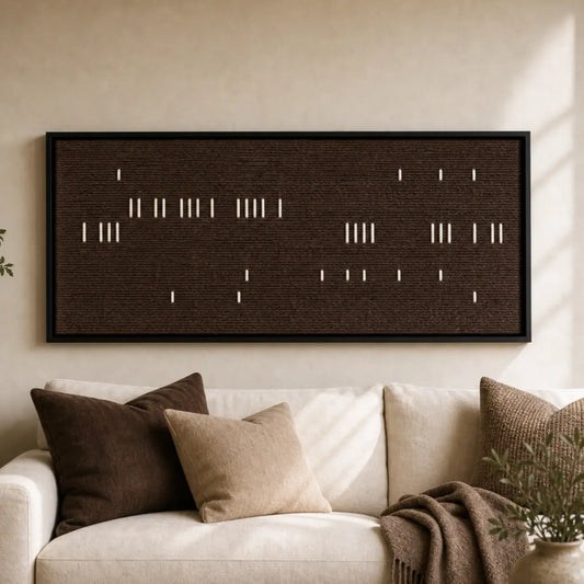 Large framed Cocoa Whispers hand-woven wall art hanging elegantly above a cozy white sofa adorned with brown pillows in a warm, neutral living room.