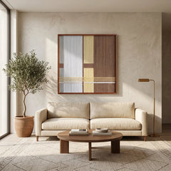 Framed fiber art tapestry with a minimalist color-block design displayed above a cream sofa in a bright, neutral-toned interior space.