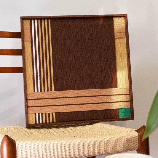 Angled view of Earthy Fragrance yarn wall art showcasing the precise geometric pattern of earth-tone stripes and tight wool stitching
