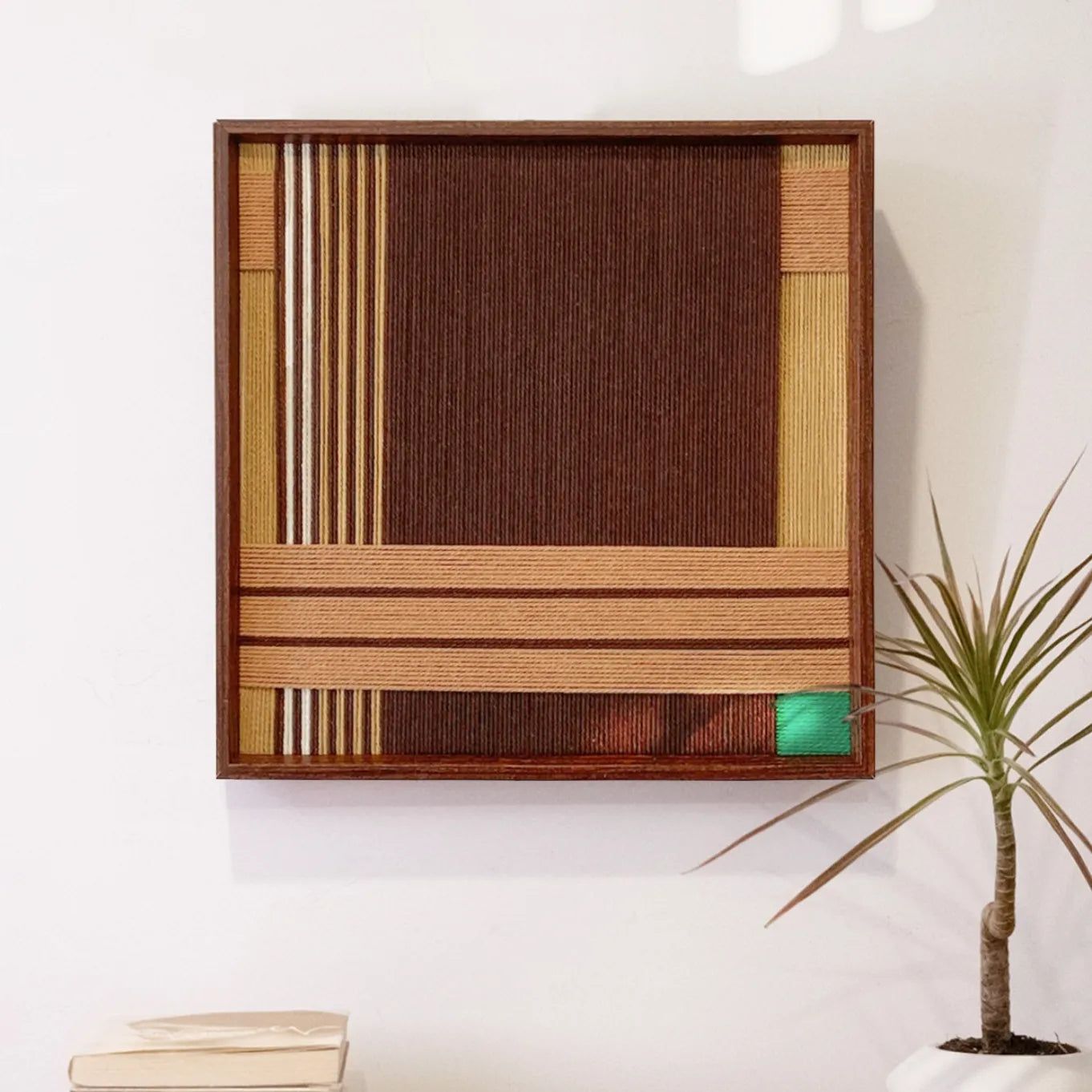 Earthy Fragrance hand-woven wool yarn wall art with alternating deep brown, tan, and emerald green vertical stripes in a natural wood frame
