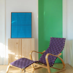 The Submersion wall hanging styled in a colorful room with a purple woven chair and green wall panel, showcasing versatile decor pairing.
