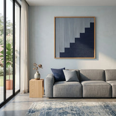 Large-scale hand-woven wool wall decor centered above a modern grey couch, creating a sophisticated focal point with deep blue tones.