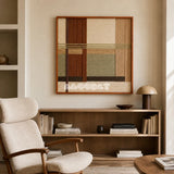 Embers of the Wild earth-tone textile wall art displayed above a low bookcase in a sunlit reading corner with a boucle chair.