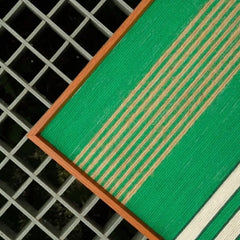 Close-up of Endless Flow hand-woven wool yarn wall art revealing looped texture and crisp transitions between green stripe panels
