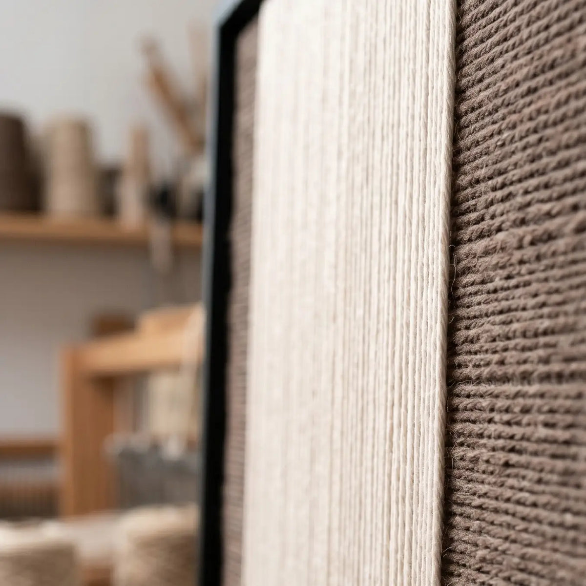 Extreme macro close-up of the Eternal Colonnade hand-woven textile art, highlighting the dimensional cream and dark brown yarn textures within the black frame.