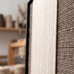 Extreme macro close-up of the Eternal Colonnade hand-woven textile art, highlighting the dimensional cream and dark brown yarn textures within the black frame.