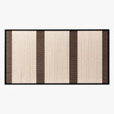 Frontal studio shot of the Eternal Colonnade rectangular hand-woven tapestry, showing cream and dark brown geometric stripes in a black frame.