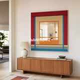 Fields of Blossoms colorful yarn-framed mirror displayed above a wood sideboard in a bright minimalist entryway.