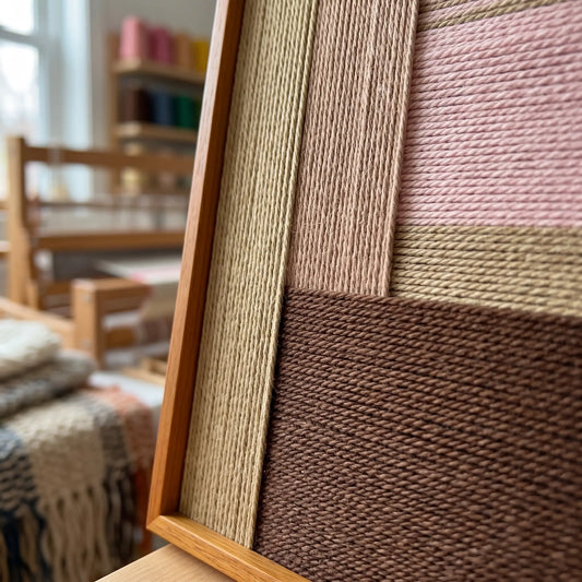 An angled close-up showing the rich, tactile hand-woven wool textures and the professional oak wood frame of the wall art.
