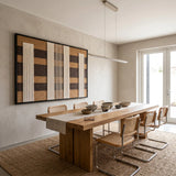 The Forgotten Gateway hand-woven tapestry hangs horizontally above a long wooden dining table, creating a refined look in a bright dining room.